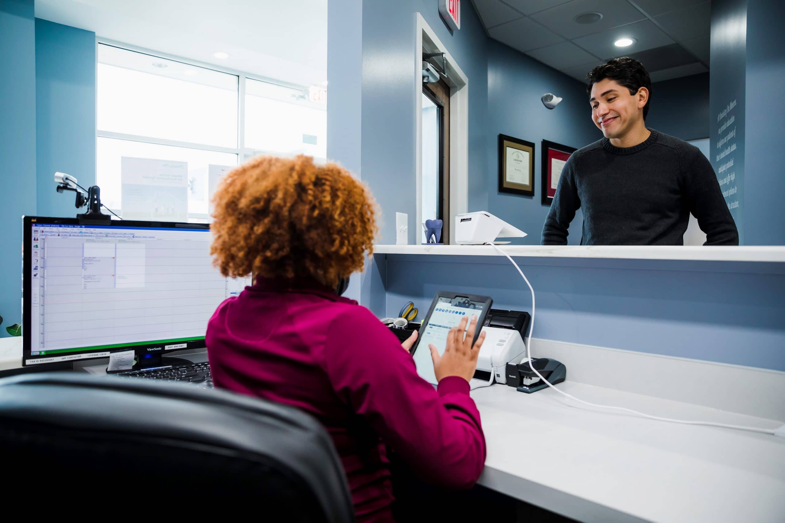 receptionist at a dental office checking in a patient